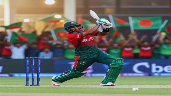 বাংলাদেশ দলের ক্রিকেটার ব্যাটিং করছেন, পেছনে বাংলাদেশের পতাকা হাতে দর্শকদের উল্লাস – খেলাধুলা এর চিত্র।